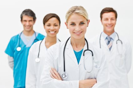 Beautiful young doctor standing with hands folded and assistant doctors in background